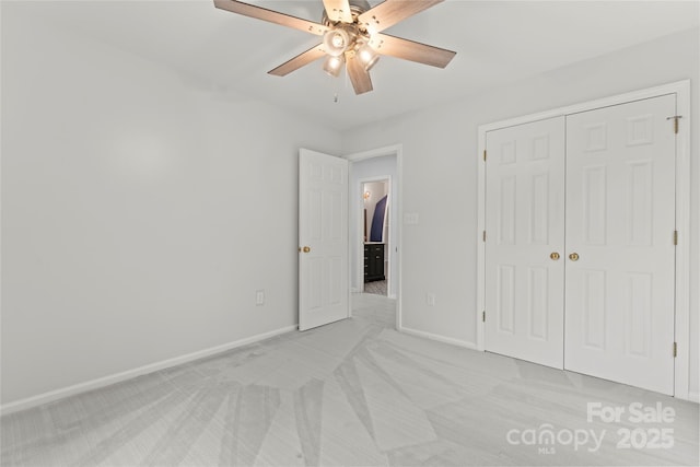unfurnished bedroom with a closet, a ceiling fan, light colored carpet, and baseboards