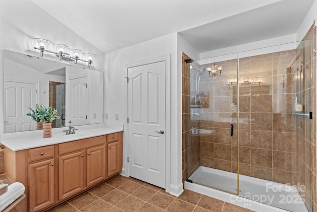 bathroom with a notable chandelier, a shower stall, lofted ceiling, and vanity