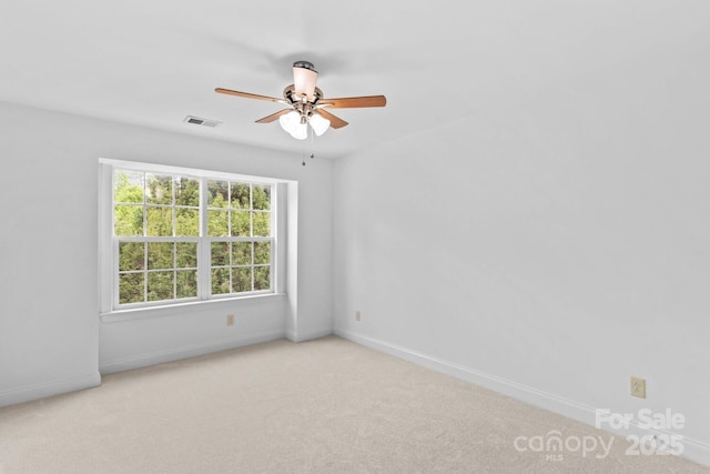 carpeted spare room with visible vents, baseboards, and ceiling fan