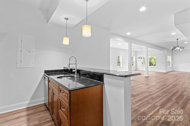 kitchen featuring brown cabinetry, stainless steel dishwasher, a peninsula, baseboards, and a sink