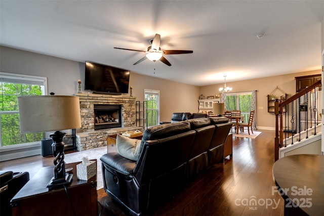 living room with a fireplace, baseboards, ceiling fan with notable chandelier, stairs, and dark wood-type flooring