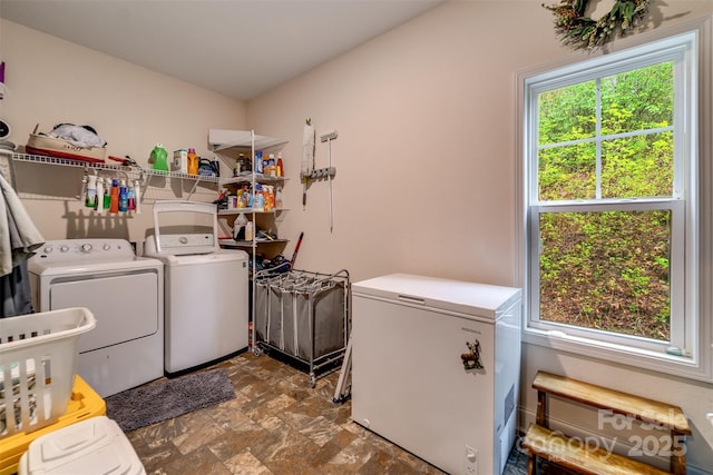 clothes washing area with washer and dryer, laundry area, and stone finish flooring