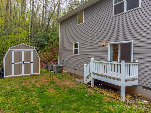 back of house featuring an outdoor structure, a wooden deck, crawl space, a lawn, and a storage shed