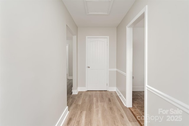 corridor with light wood-type flooring and baseboards