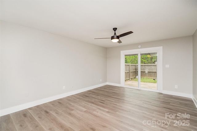 empty room with wood finished floors, a ceiling fan, and baseboards