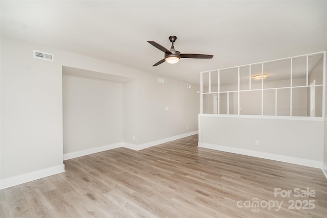 empty room with ceiling fan, light wood-style flooring, and baseboards