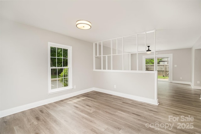 unfurnished room featuring healthy amount of natural light, wood finished floors, baseboards, and ceiling fan