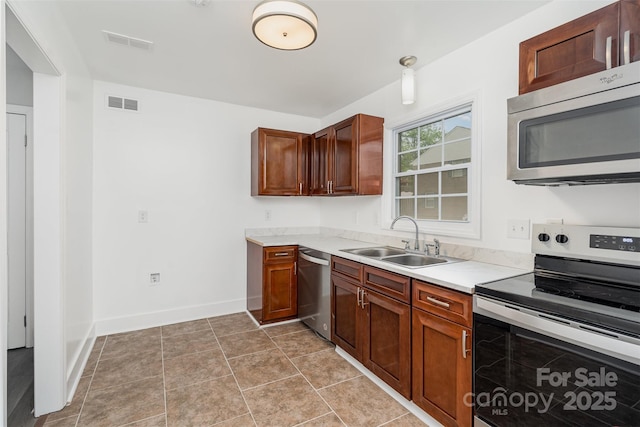 kitchen with appliances with stainless steel finishes, a sink, light countertops, and baseboards