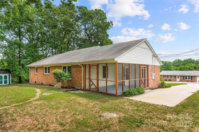 115 K M Murphy Rd, Gastonia, NC 28056 - rear view of house with a yard, brick siding, a storage unit, an outbuilding, and a sunroom