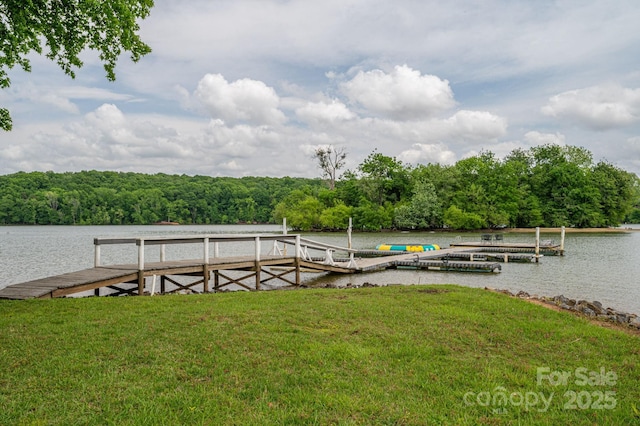 view of dock featuring a lawn, a water view, and a forest view