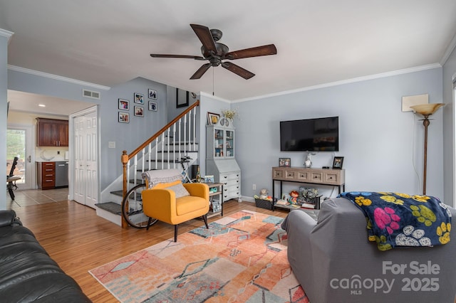 living room featuring crown molding, stairs, a ceiling fan, wood finished floors, and visible vents