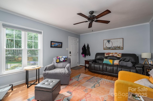 living room with crown molding, a ceiling fan, light wood finished floors, and baseboards