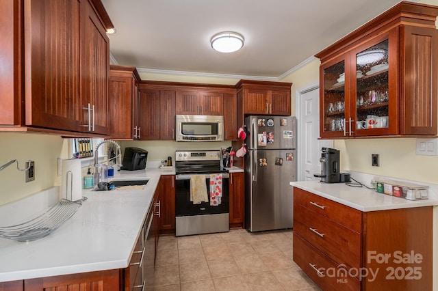 kitchen with a sink, light countertops, light tile patterned floors, glass insert cabinets, and stainless steel appliances