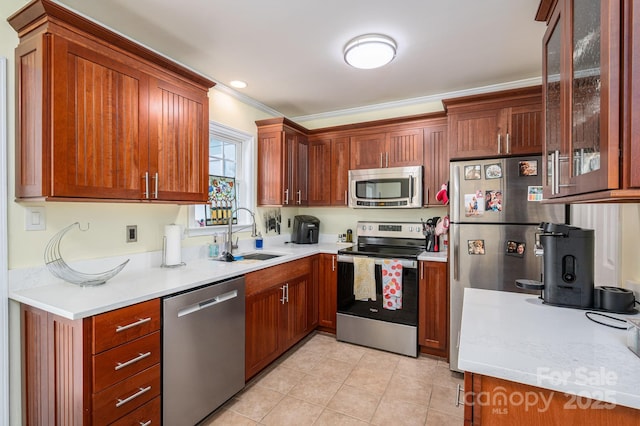 kitchen with light tile patterned flooring, glass insert cabinets, light countertops, a sink, and stainless steel appliances
