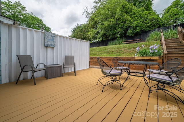 wooden deck with fence, outdoor dining space, and a yard