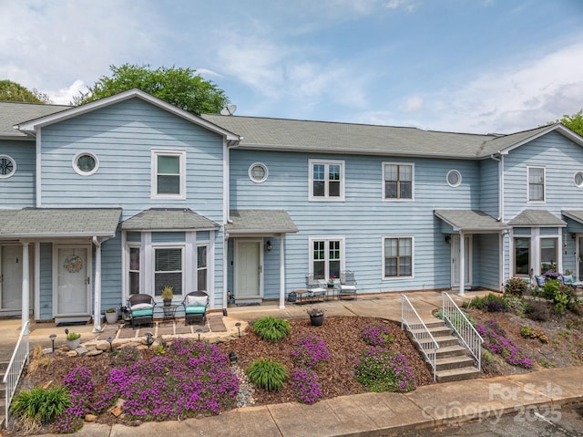 townhome / multi-family property with a patio and a shingled roof