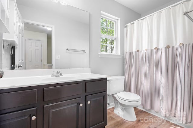 full bath with toilet, a shower with curtain, vanity, and wood finished floors