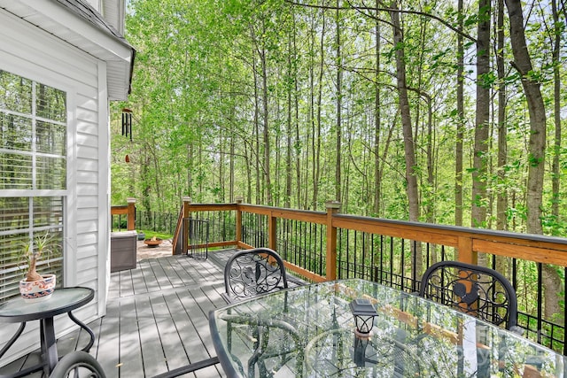 deck featuring outdoor dining space and a forest view