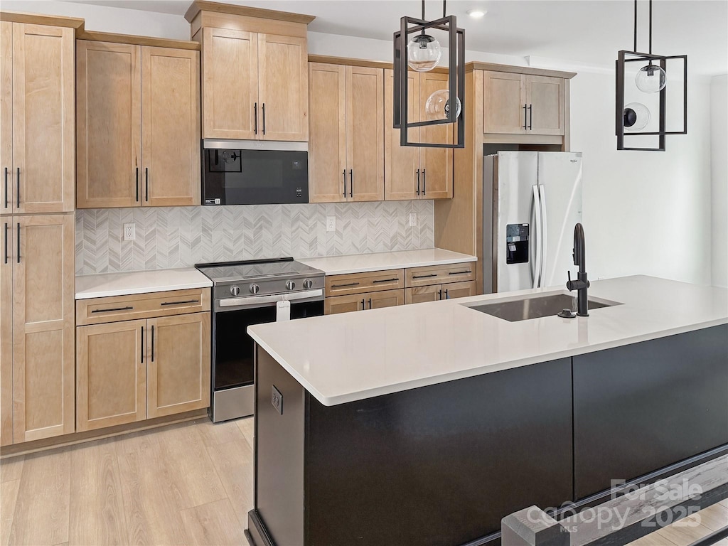 kitchen featuring decorative backsplash, a sink, stainless steel appliances, light countertops, and light wood-type flooring