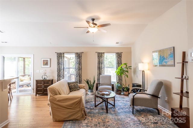 living room with lofted ceiling, ceiling fan, visible vents, baseboards, and wood finished floors
