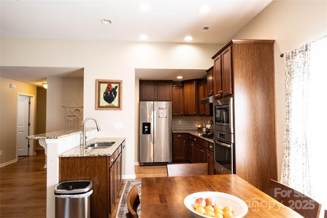 kitchen featuring light stone counters, a sink, appliances with stainless steel finishes, and baseboards