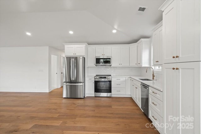 2429/2425 Ellen Ave, Charlotte, NC 28208 - kitchen with lofted ceiling, a sink, white cabinetry, and appliances with stainless steel finishes