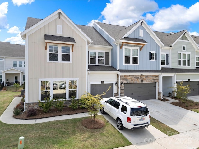 view of property with board and batten siding, a garage, concrete driveway, a shingled roof, and stone siding