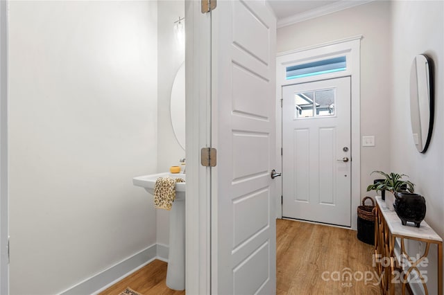 foyer entrance with crown molding, baseboards, and light wood-type flooring