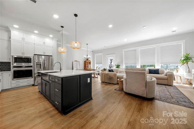 kitchen with appliances with stainless steel finishes, white cabinetry, and open floor plan