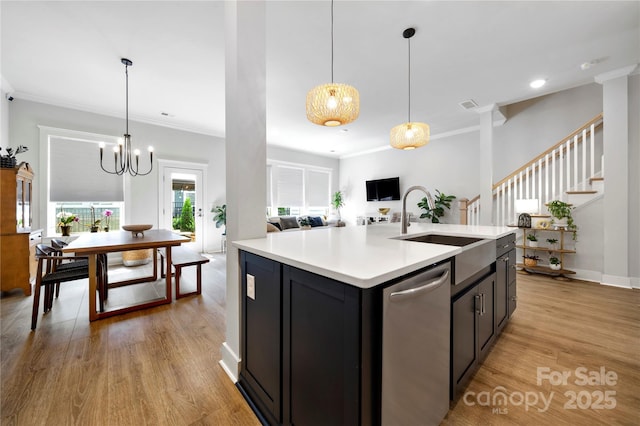kitchen featuring stainless steel dishwasher, open floor plan, light countertops, a sink, and light wood finished floors