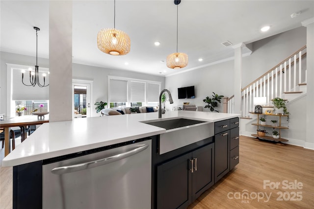 kitchen featuring stainless steel dishwasher, open floor plan, ornamental molding, and a sink