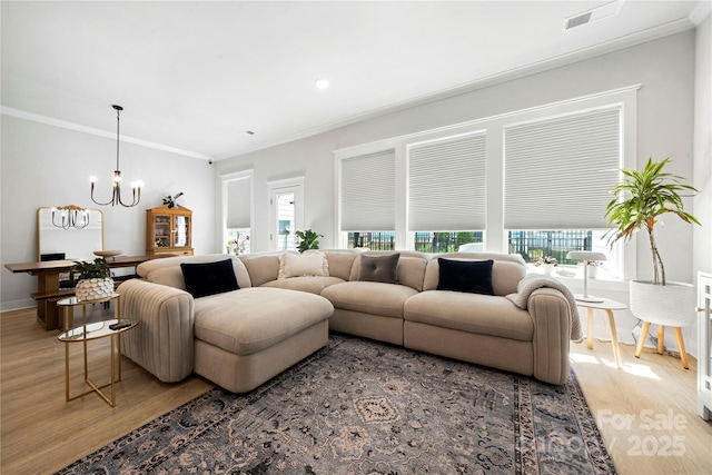 living area featuring crown molding, a chandelier, light wood-style flooring, and visible vents