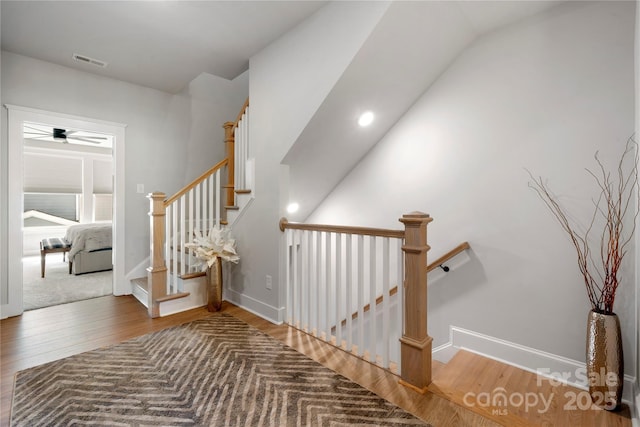 stairway with baseboards, a ceiling fan, wood finished floors, and visible vents