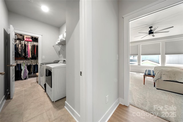 clothes washing area featuring independent washer and dryer, a ceiling fan, laundry area, and baseboards