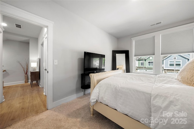 bedroom featuring visible vents, baseboards, and light carpet