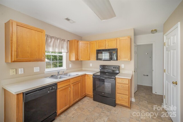 kitchen with visible vents, stone finish floor, light countertops, a sink, and black appliances