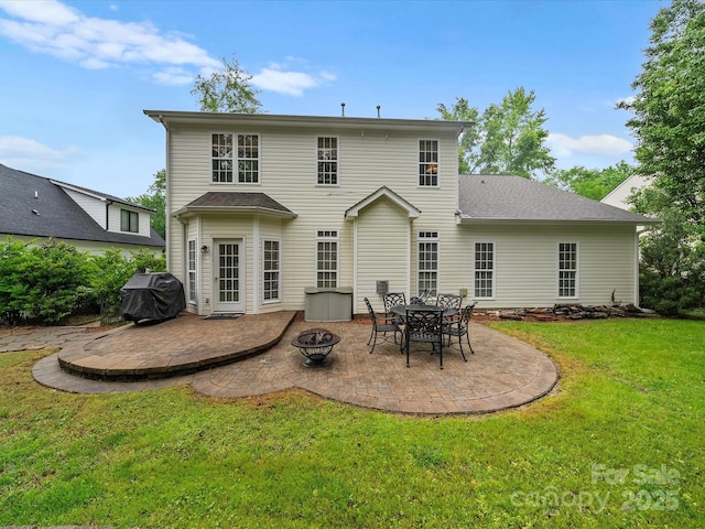 rear view of house with a patio, a lawn, and an outdoor fire pit