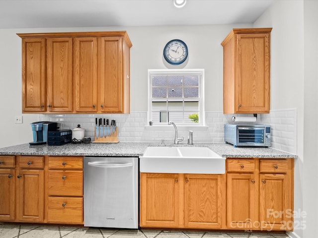 kitchen featuring light stone counters, decorative backsplash, stainless steel dishwasher, a sink, and a toaster