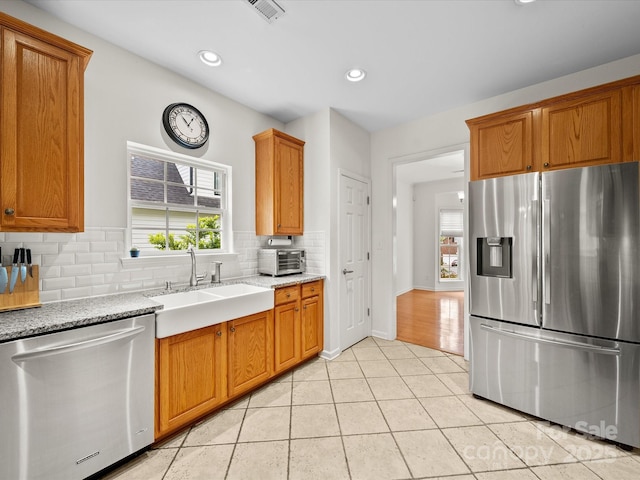 kitchen featuring a sink, light tile patterned flooring, visible vents, backsplash, and appliances with stainless steel finishes
