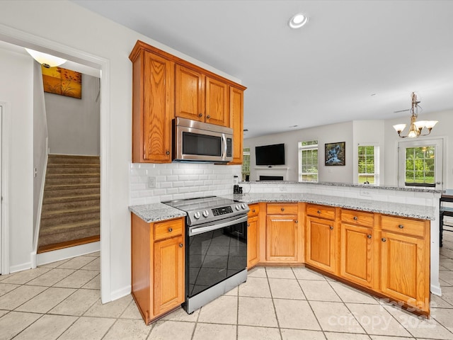 kitchen with tasteful backsplash, light stone counters, appliances with stainless steel finishes, a peninsula, and light tile patterned flooring
