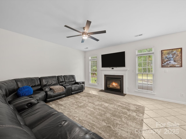 living area featuring light tile patterned floors, visible vents, ceiling fan, and a wealth of natural light