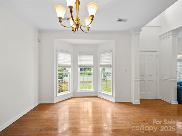 unfurnished dining area with an inviting chandelier, ornamental molding, light wood finished floors, baseboards, and visible vents