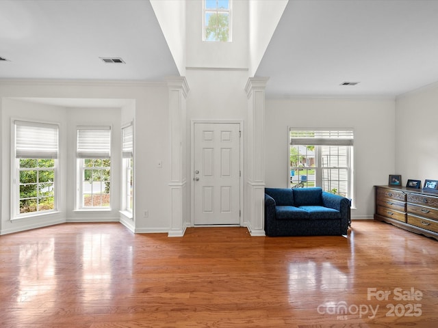 entrance foyer with baseboards, visible vents, ornamental molding, and light wood-style flooring