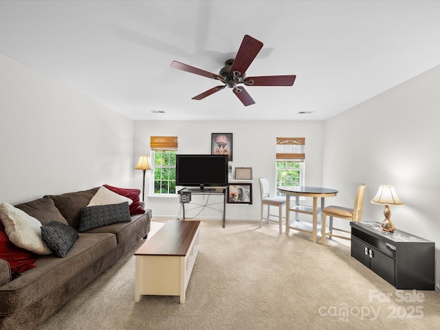 living room with a wealth of natural light, visible vents, a ceiling fan, and carpet
