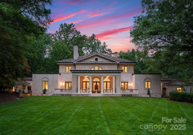 5030 Hardison Rd, Charlotte, NC 28226 - back of property at dusk featuring a chimney, a lawn, and stucco siding