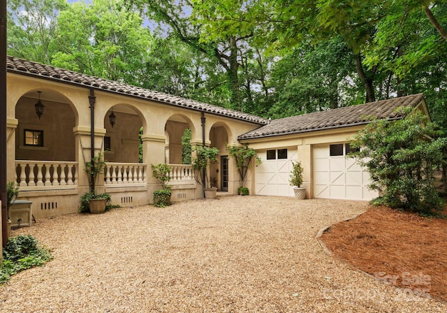 5030 Hardison Rd, Charlotte, NC 28226 - mediterranean / spanish-style house featuring a porch, gravel driveway, stucco siding, and a tiled roof
