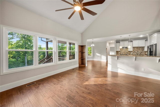 444 Snapdragon Dr, Clover, SC 29710 - unfurnished living room featuring baseboards, ceiling fan, high vaulted ceiling, wood finished floors, and a chandelier