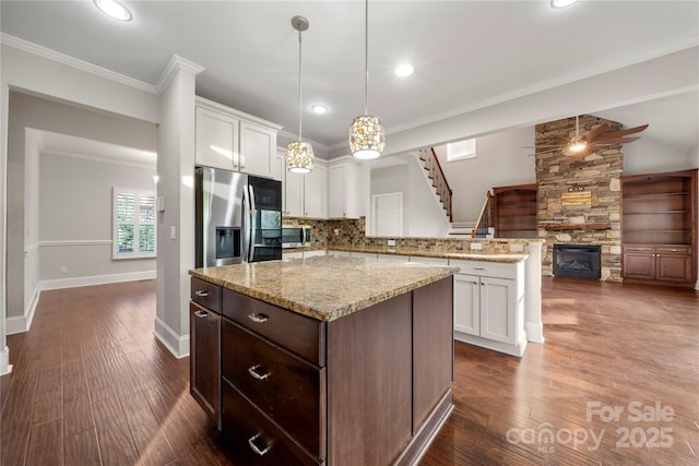 444 Snapdragon Dr, Clover, SC 29710 - kitchen with a peninsula, stainless steel appliances, a fireplace, white cabinetry, and backsplash