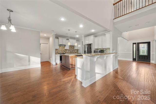 444 Snapdragon Dr, Clover, SC 29710 - kitchen featuring appliances with stainless steel finishes, light stone counters, decorative backsplash, a peninsula, and dark wood-style flooring