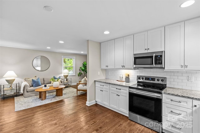 kitchen with stainless steel appliances, open floor plan, recessed lighting, white cabinetry, and tasteful backsplash